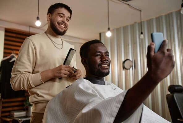 Barber and loyal customer smiling after appointment