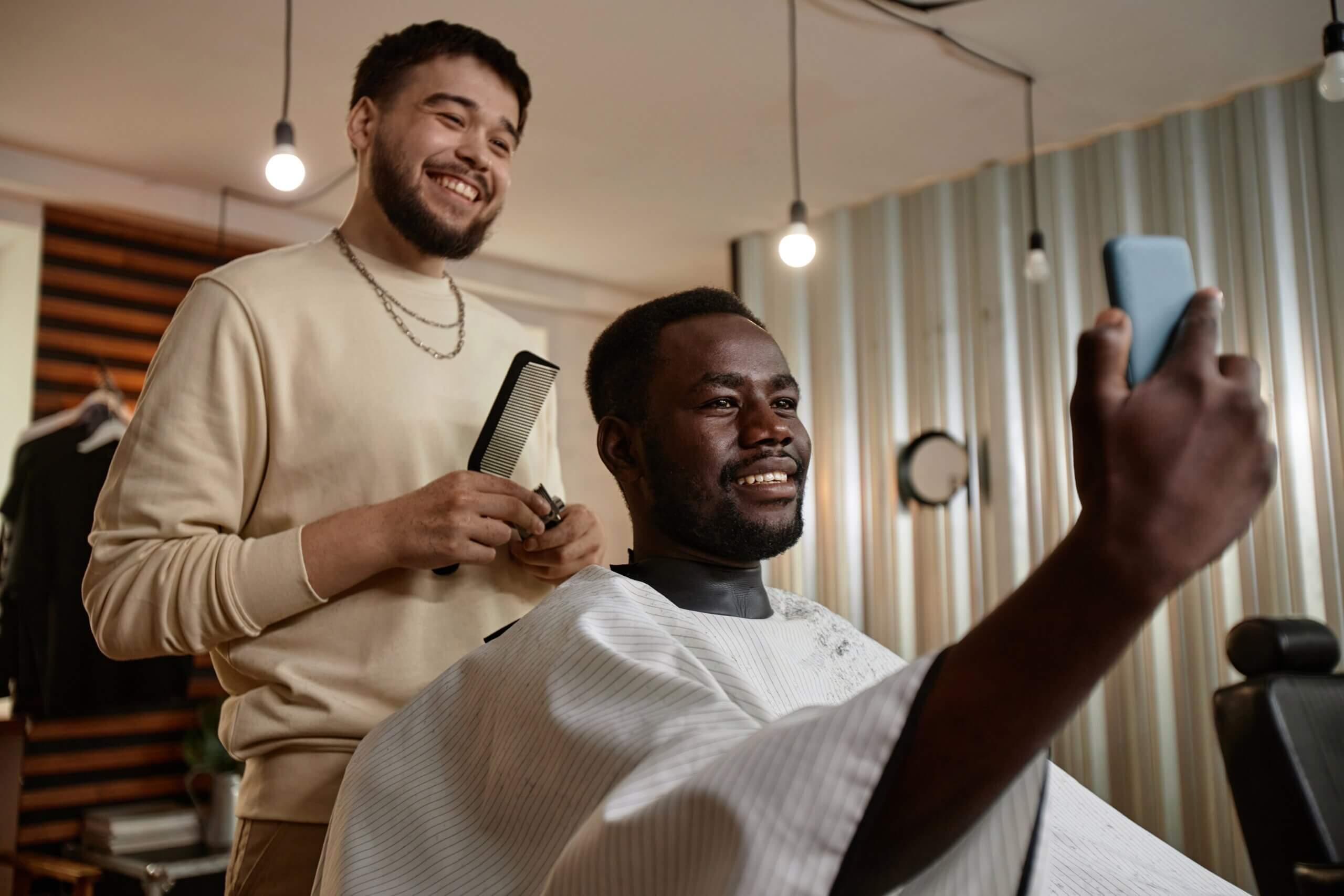 Barber and loyal customer smiling after appointment